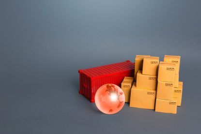 Na imagem, um globo terrestre, um container vermelho e caixas de papelão